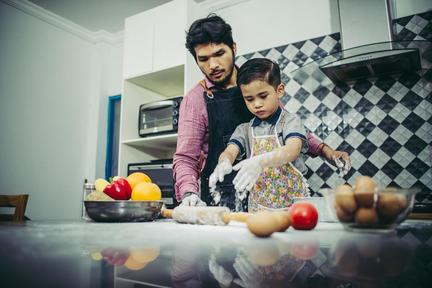 Dad teaches his son how to cook in kitchen photo