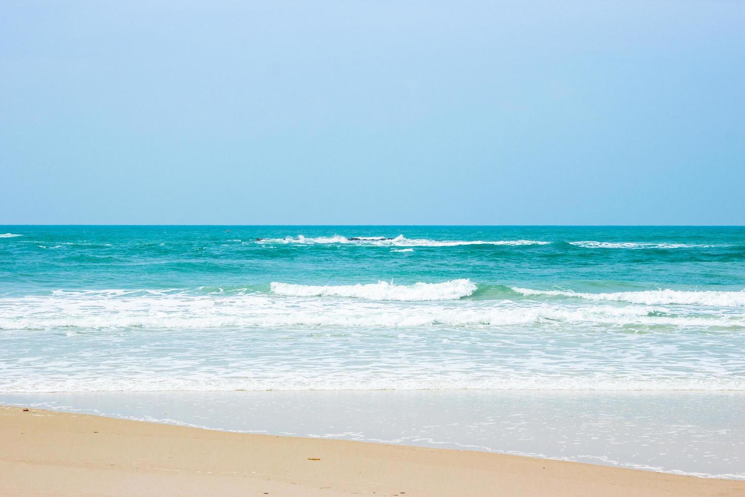 Sand and water at beach with clear blue sky photo