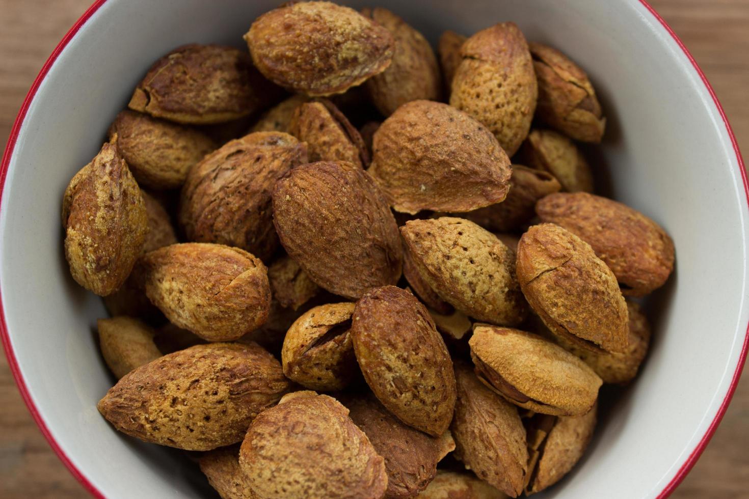 Close-up of almonds in white bowl on wooden table photo