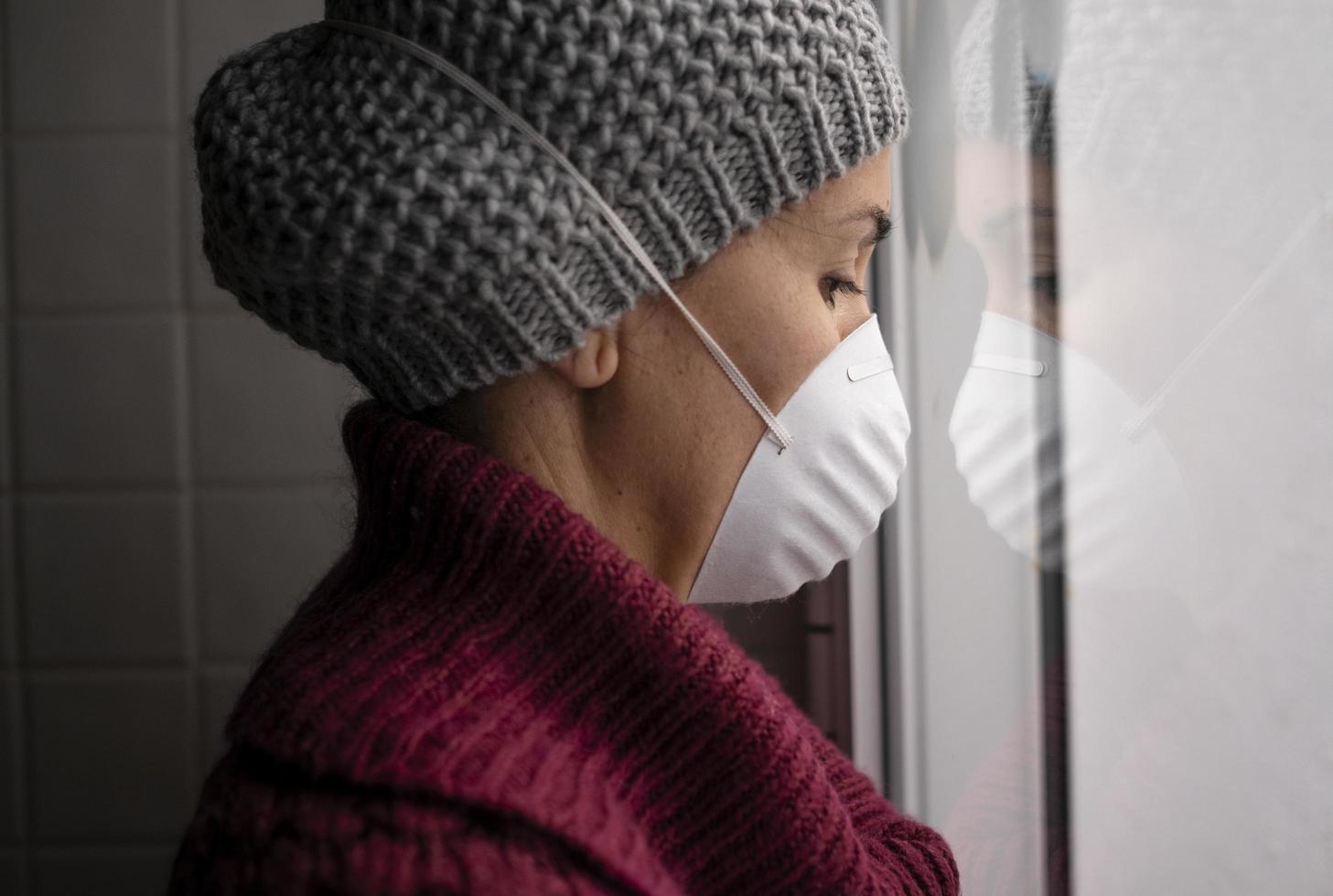 Woman with face mask looking out a window photo