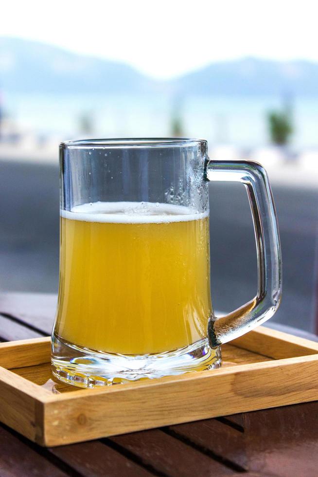 Glass of beer in wooden tray on table photo