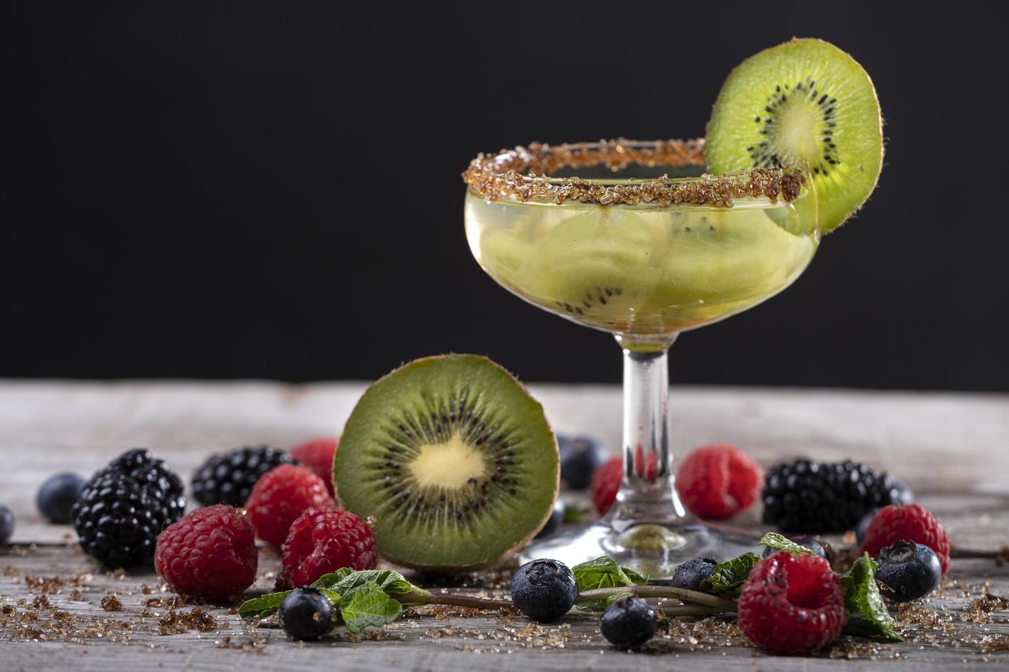 kiwi cocktail on a wooden base decorated with fruits of the forest photo