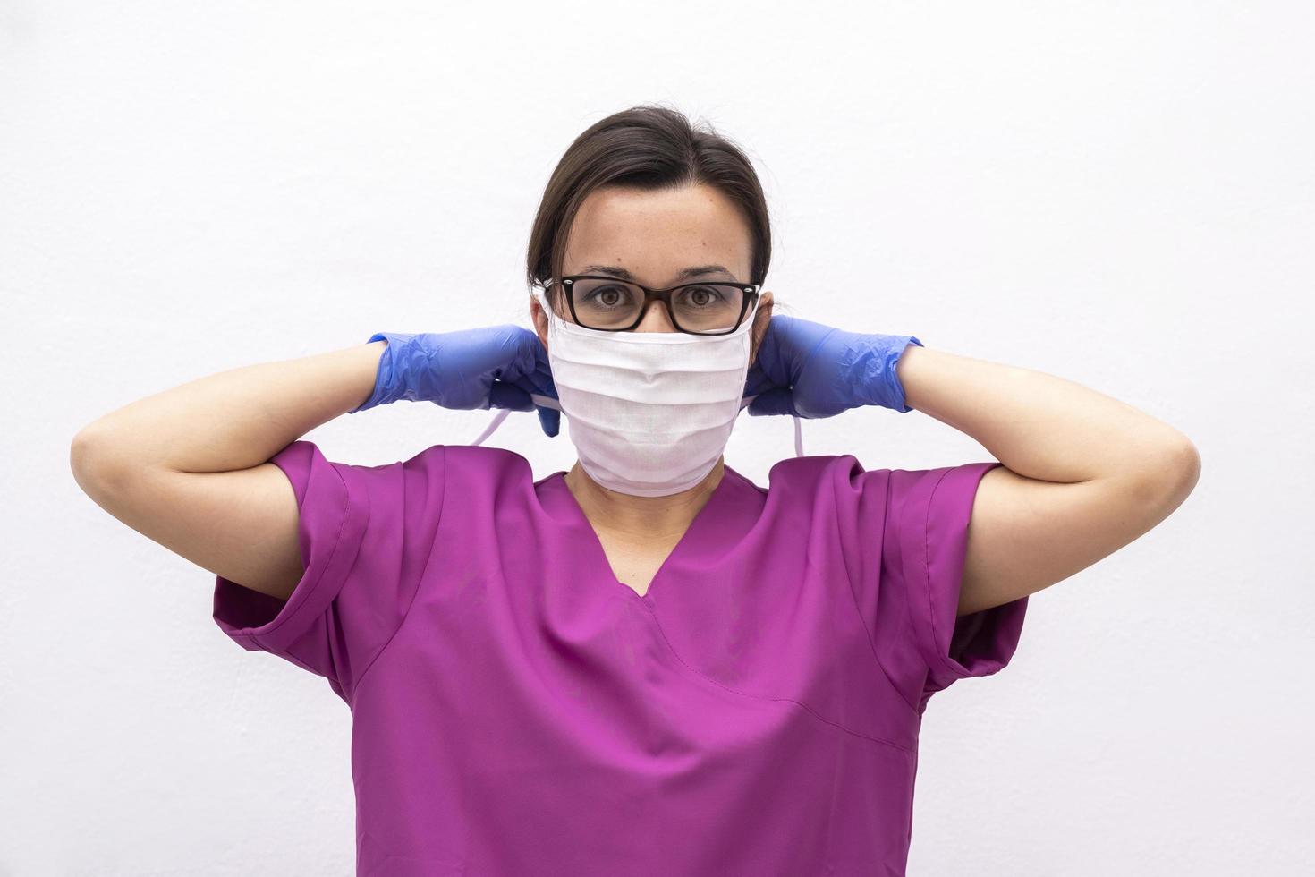 Attractive Female Doctor or Nurse Putting on Protective Face Mask. photo