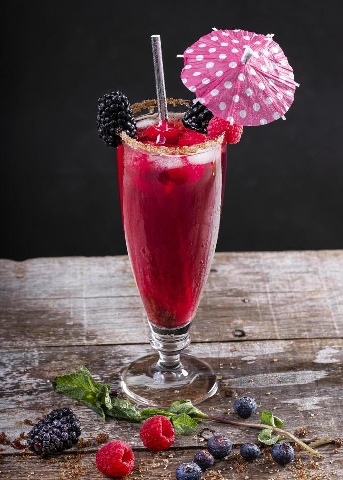 Cóctel de frutas del bosque en un vaso sobre una base de madera decorada con moras foto