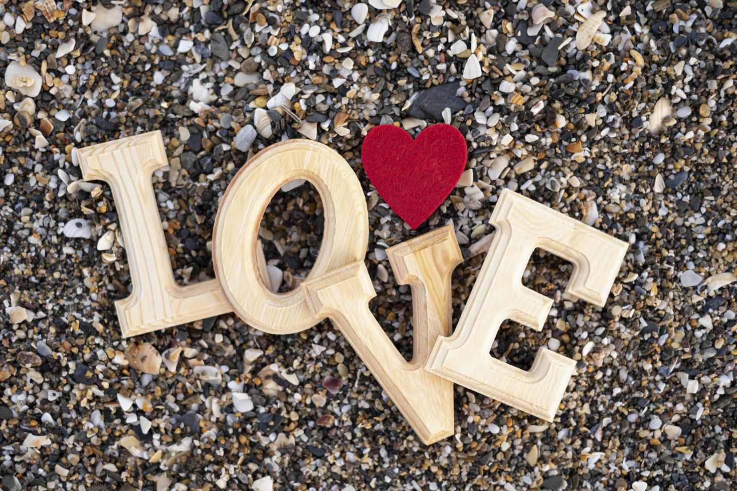 Wooden letters forming the word love with a red heart on a background of beach sand. concept of san valentine photo