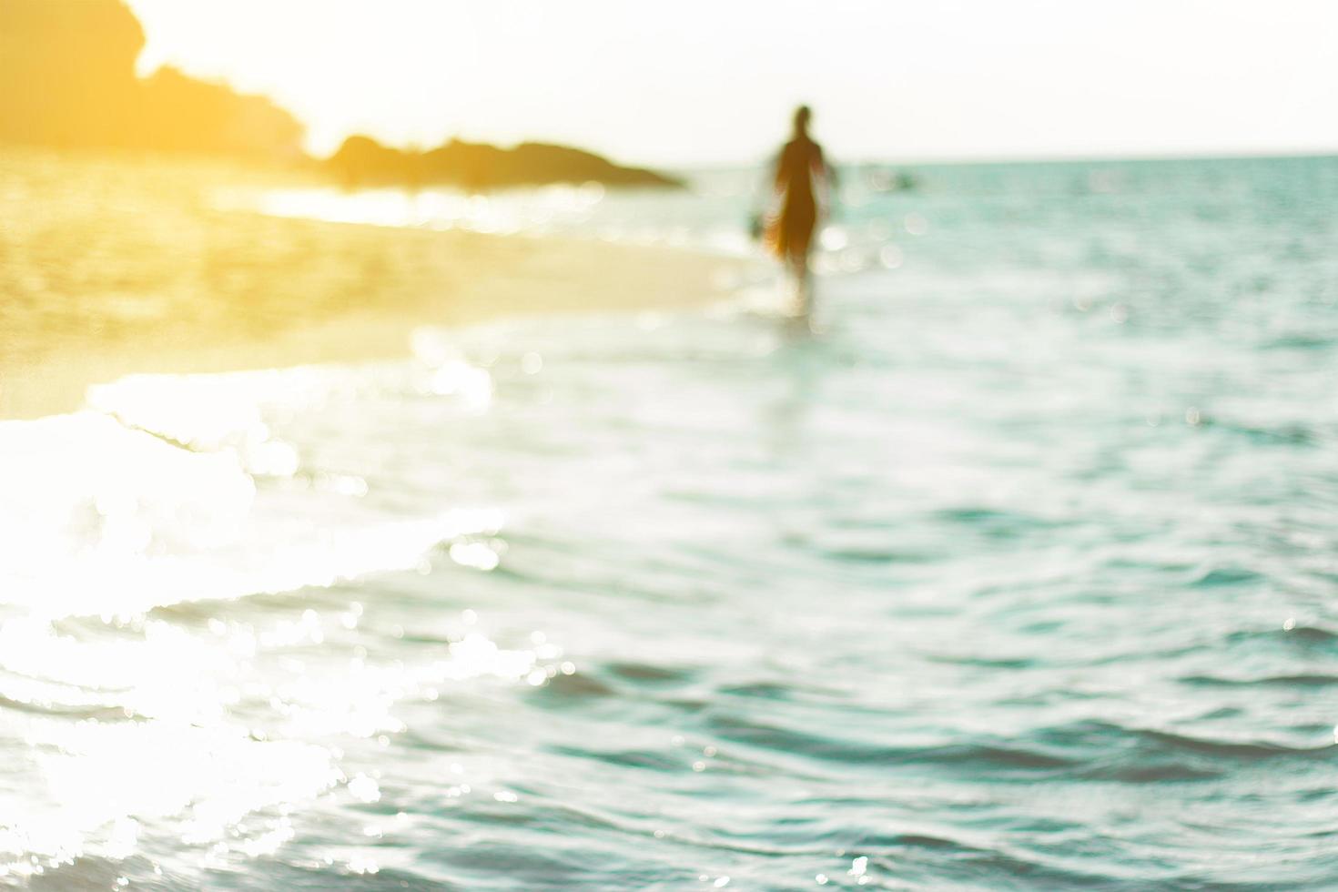 Persona borrosa caminando en el agua en la playa foto