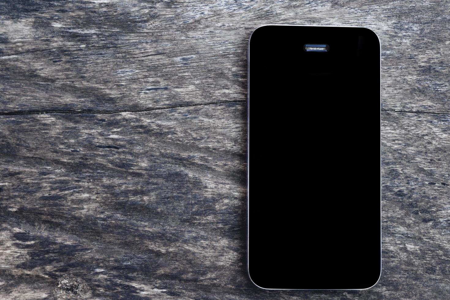 Top view of Mockup black screen mobile smartphone on blank old wooden table background. Overhead view phone Flat lay and copy space for business concept. photo