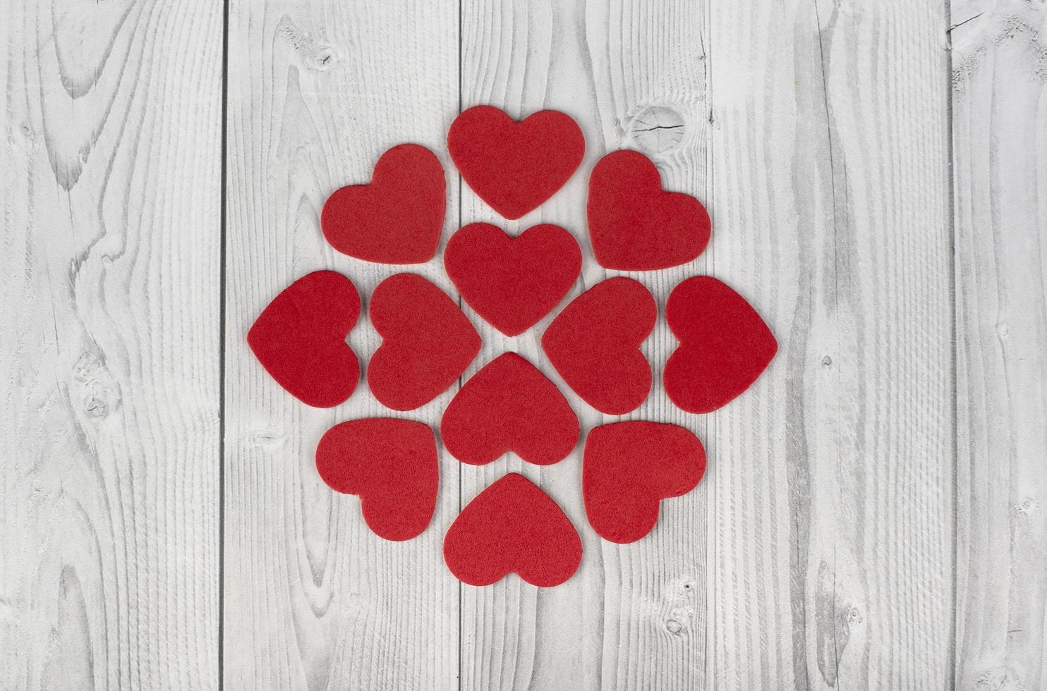 Corazones rojos formando una figura geométrica en el centro de un fondo de madera blanco y gris. concepto de dia de san valentin foto