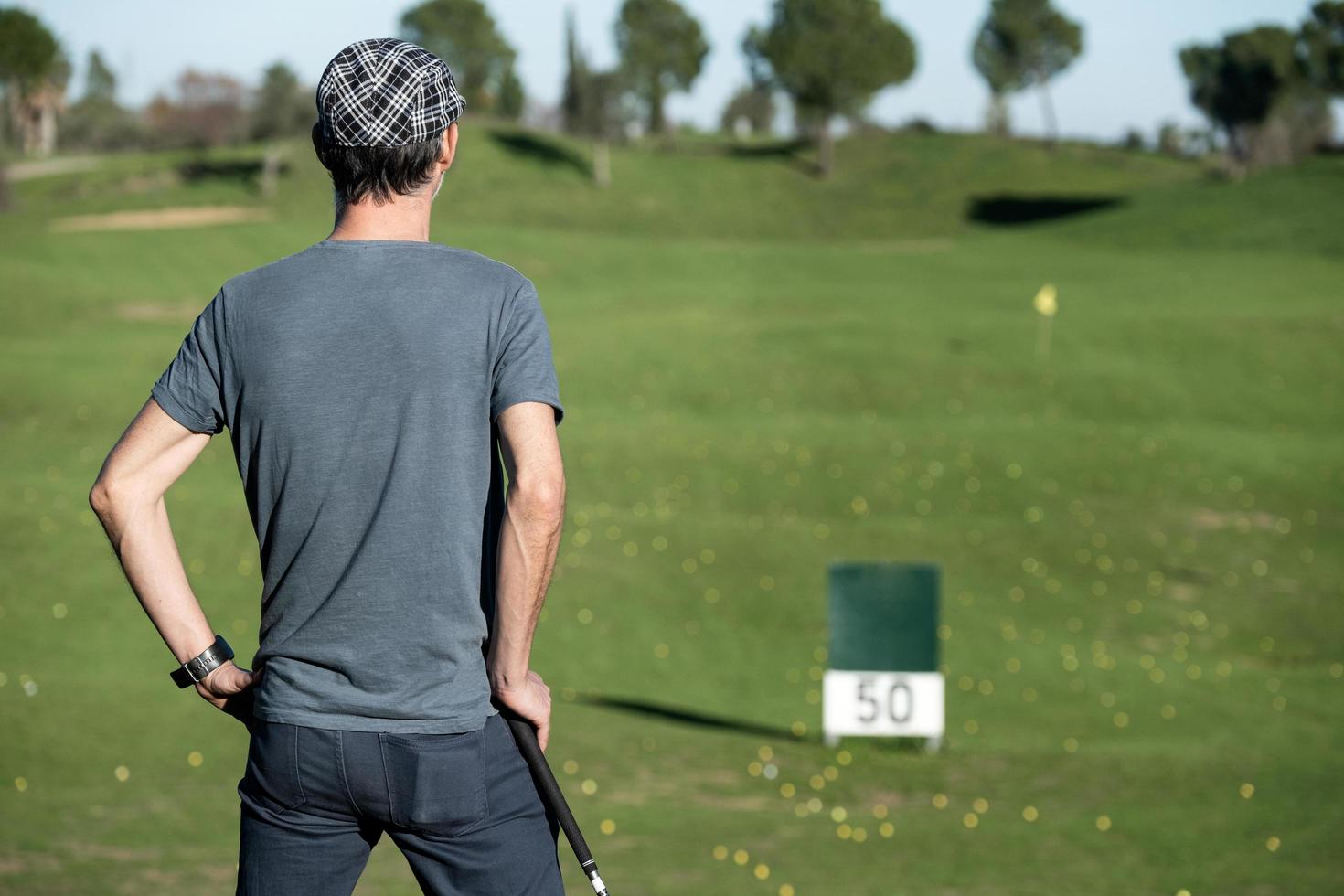 Golfista de espaldas apoyado en un club de golf mirando el horizonte foto