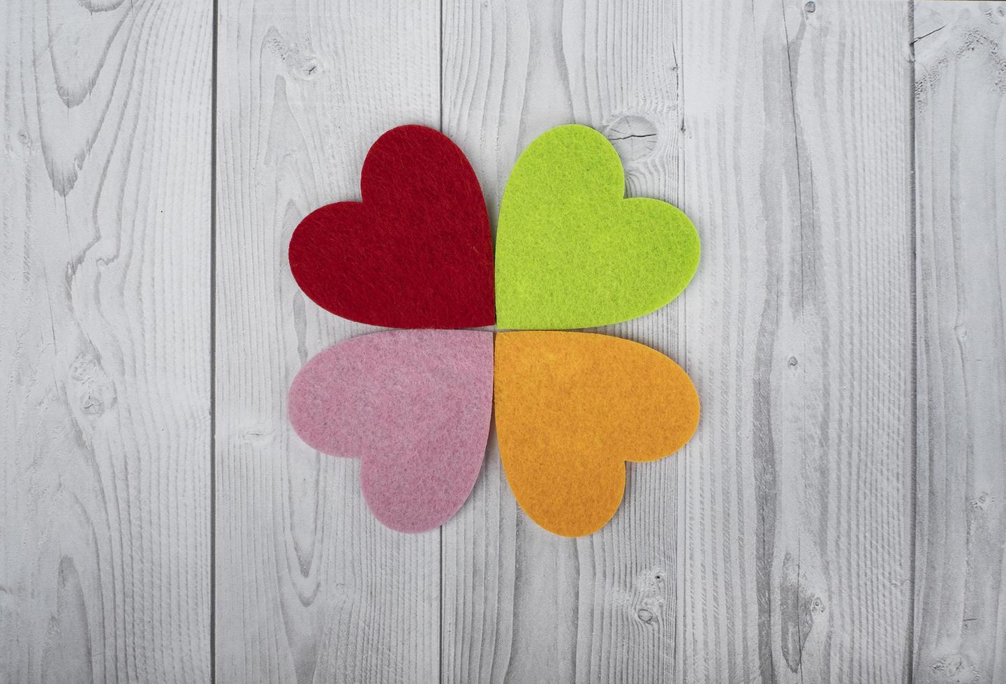 cuatro corazones de colores sobre un fondo de madera gris y blanco. concepto de st. día de San Valentín foto