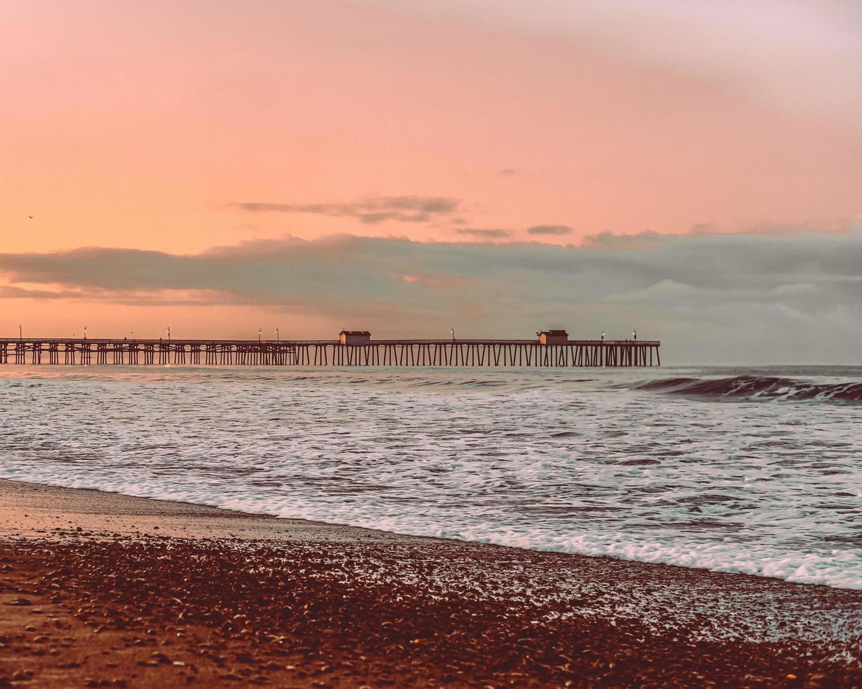 Sea waves crashing on shore during sunset photo