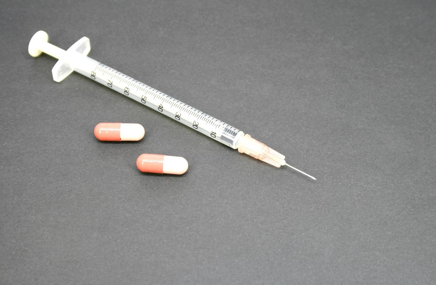 syringe with tablet on black photo