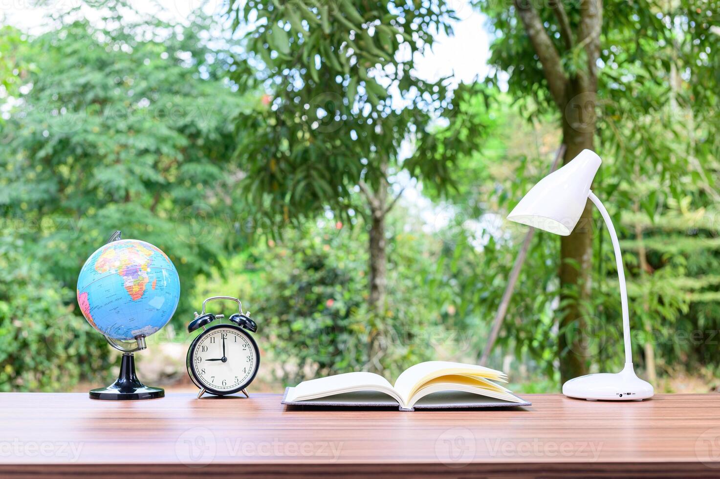 A table with a globe, an open book and an alarm clock in the background photo