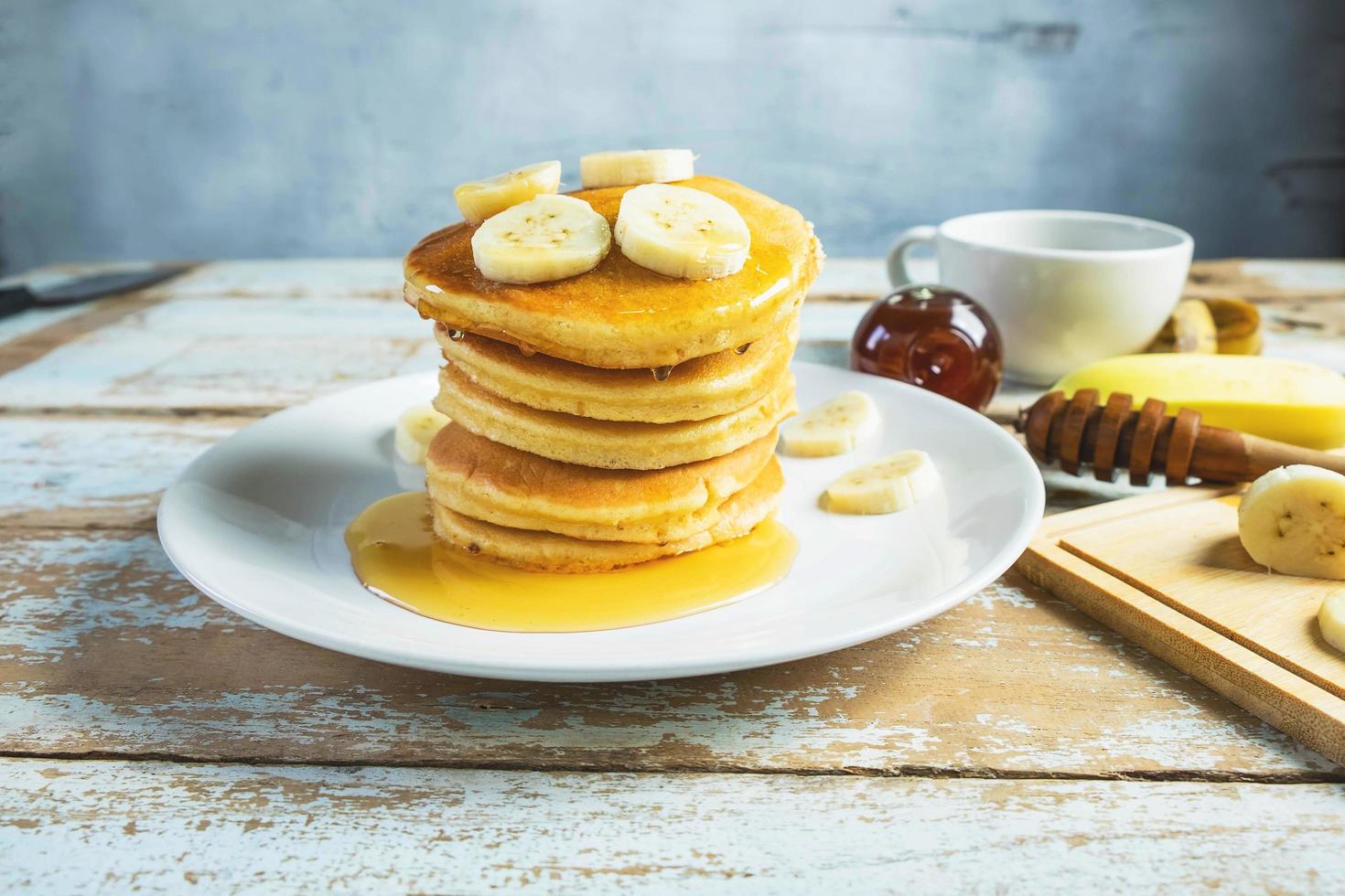 Pancakes topped with honey and bananas on the table photo