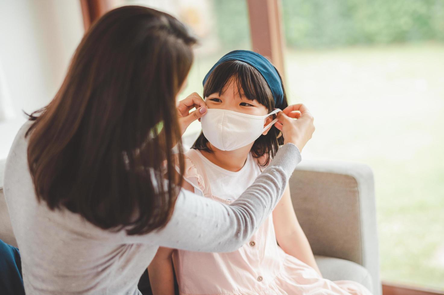 Mother placing mask on daughter photo