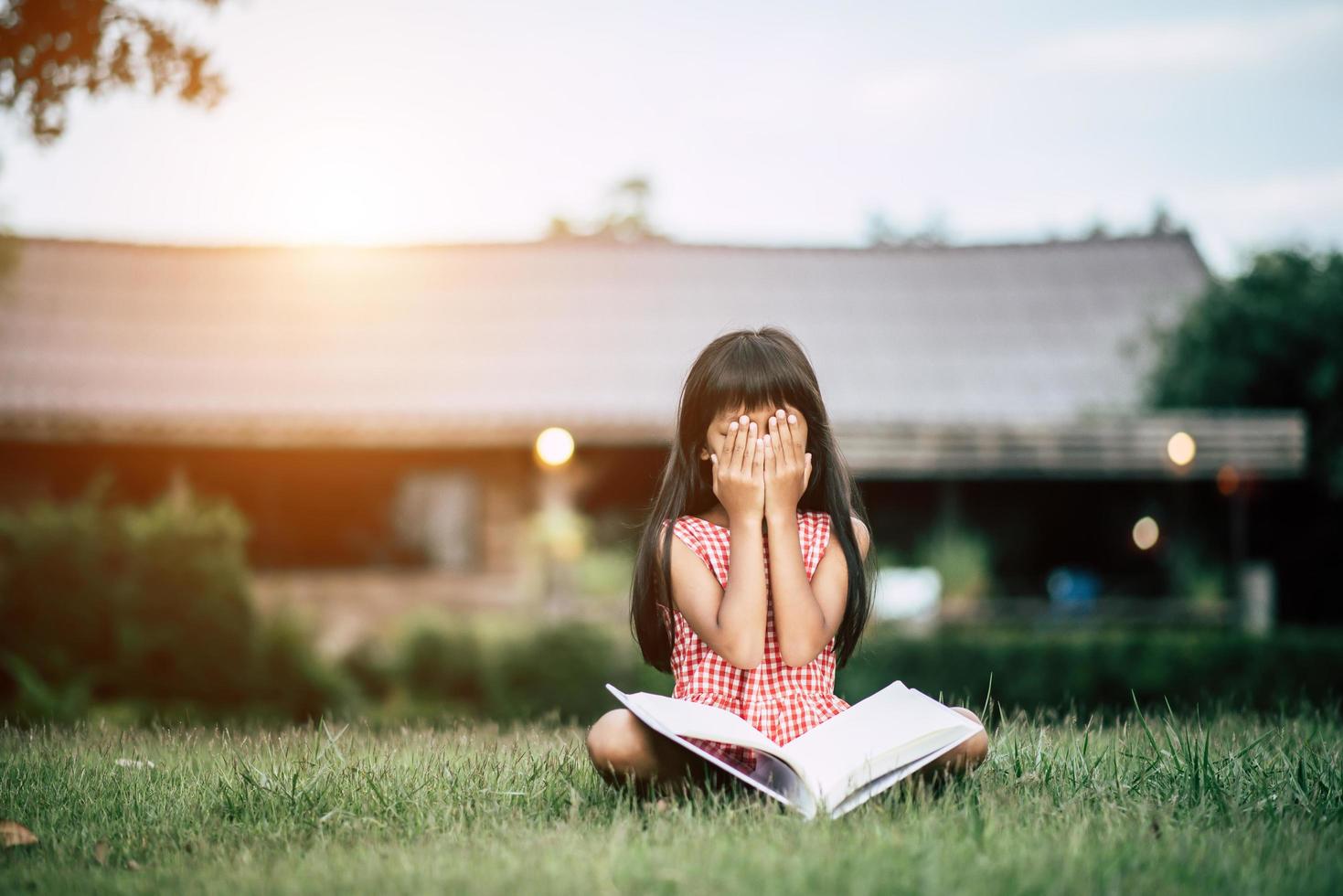 Young girl reading in garden outside her house photo