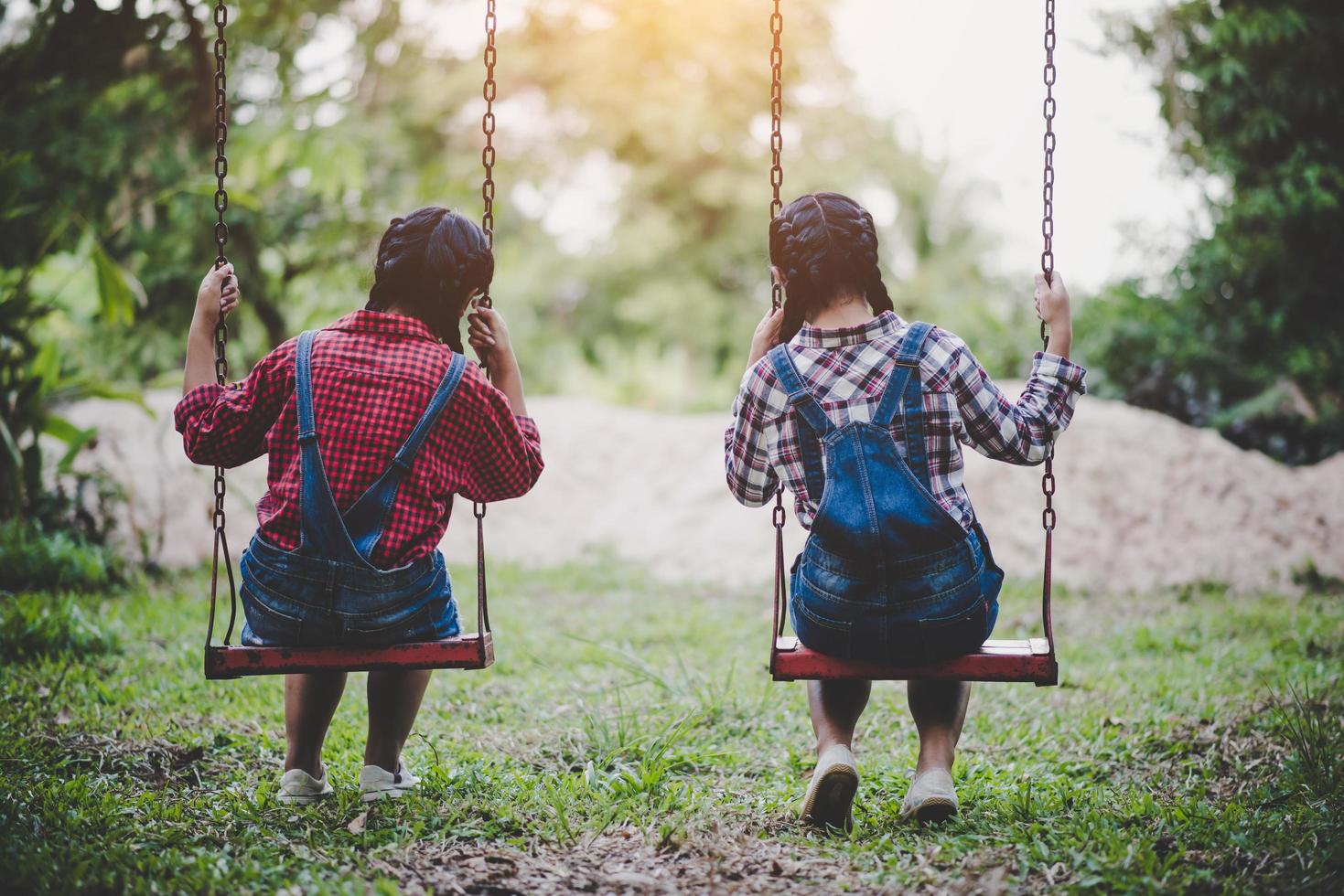 Two young girls sitting on a swing together photo