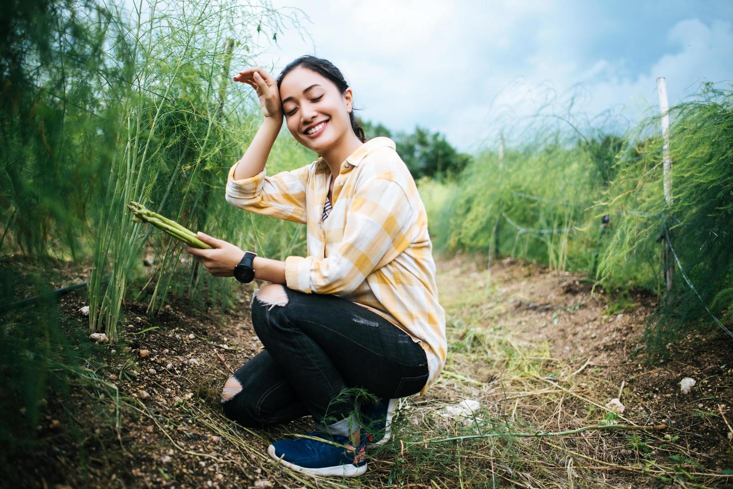 Bastante joven agricultor cosechando asparagu fresco en el campo foto