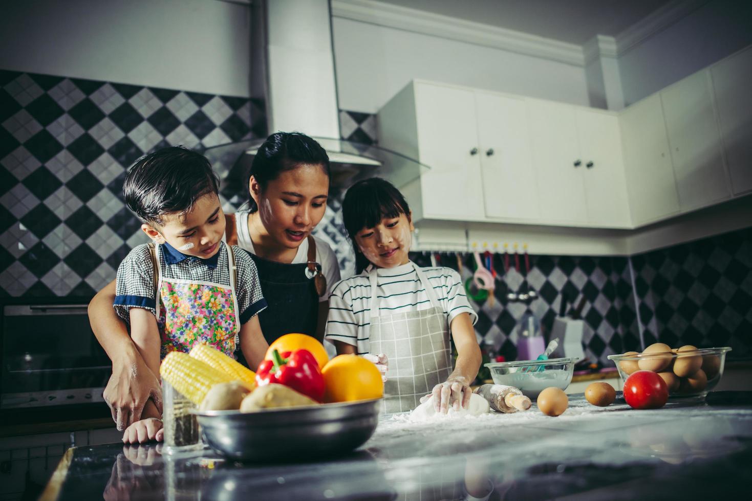 Mom teaches her children how to prepare pizza dough photo