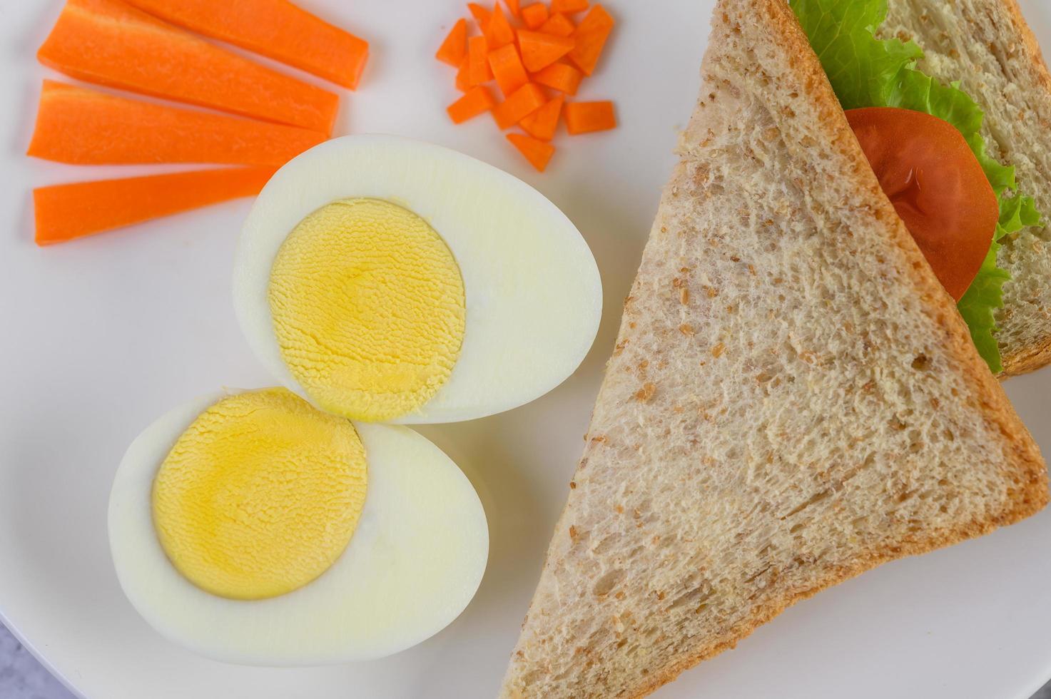 A fried egg on toast topped with pepper seeds with carrots and spring onions photo