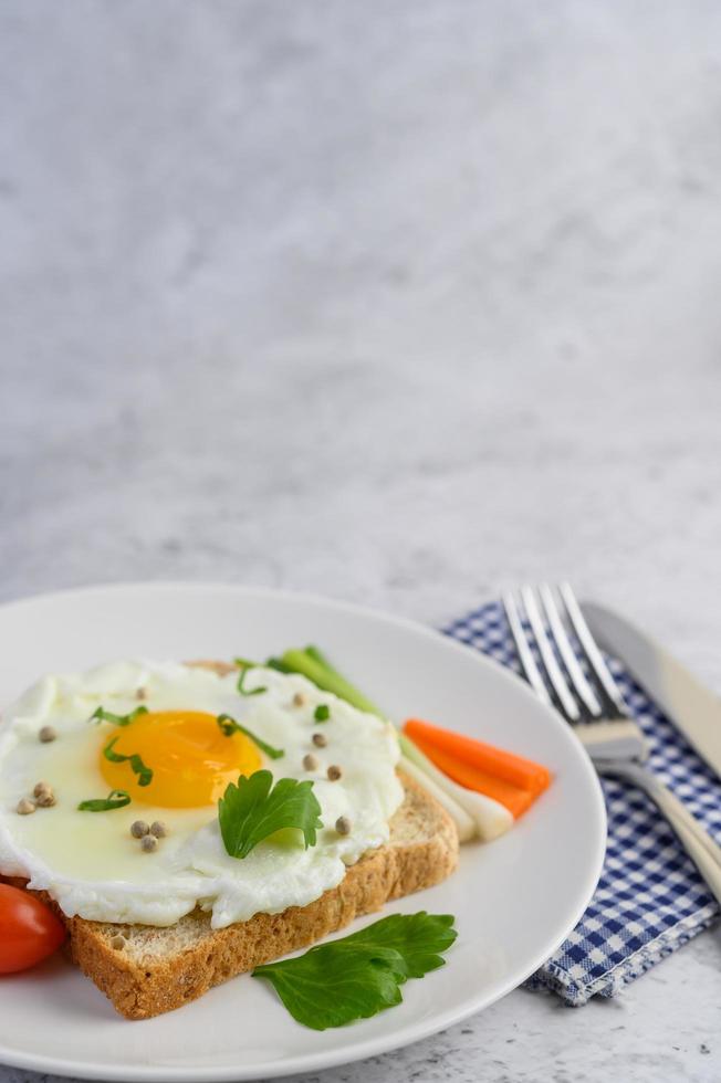 A fried egg on toast topped with pepper seeds with carrots and spring onions photo