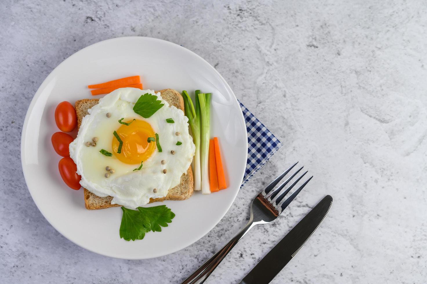 un huevo frito sobre una tostada cubierta con semillas de pimiento con zanahorias y cebolletas foto