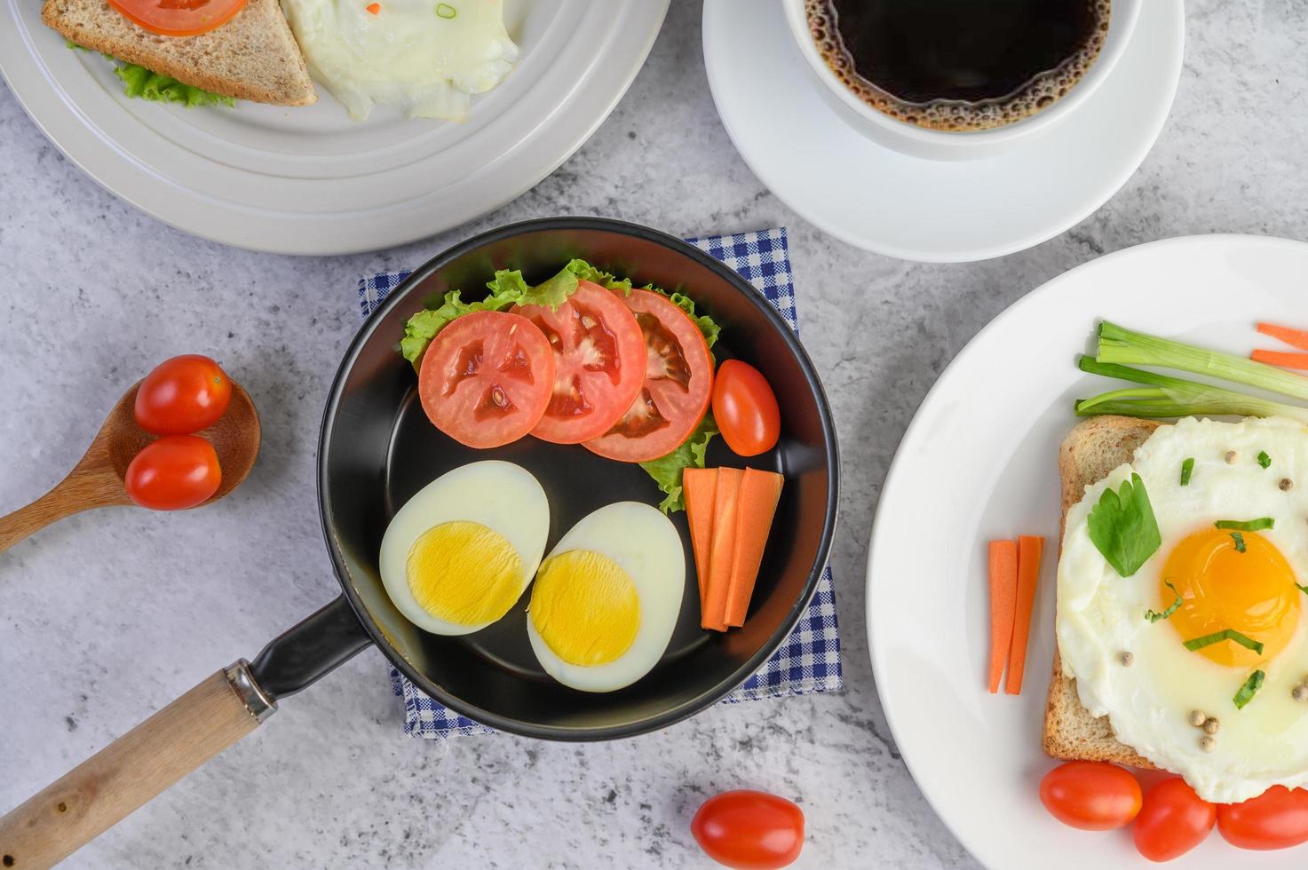 Boiled eggs, carrots and tomatoes with spoon and coffee cup photo