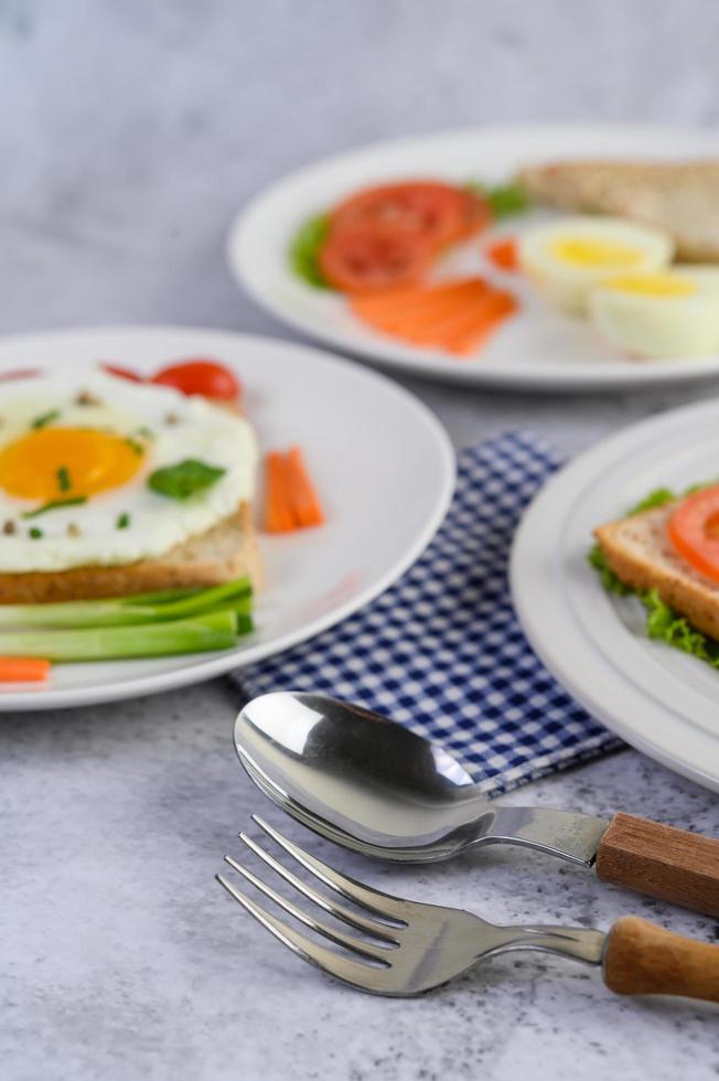 A fried egg with toast, carrots, baby corn and spring onions photo