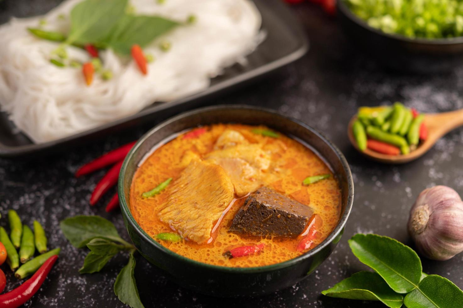 pollo al curry en una taza negra con fideos de arroz foto