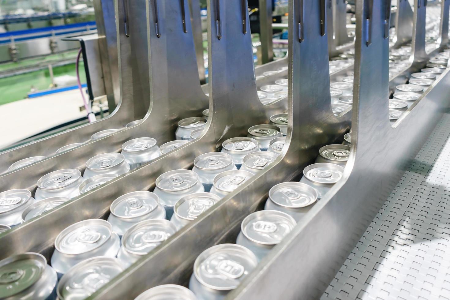 Conveyor line carrying thousands aluminum beverage cans at factory. Concept of industrial growth photo
