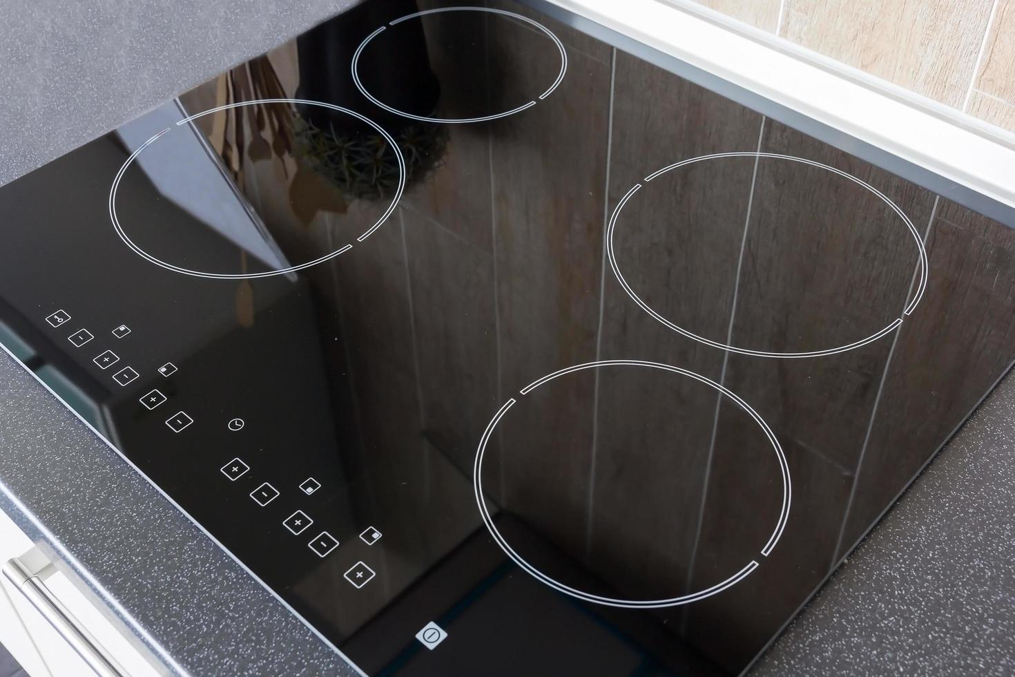 Close up view of an electrical kitchen induction ceramic hob with kitchen furniture photo