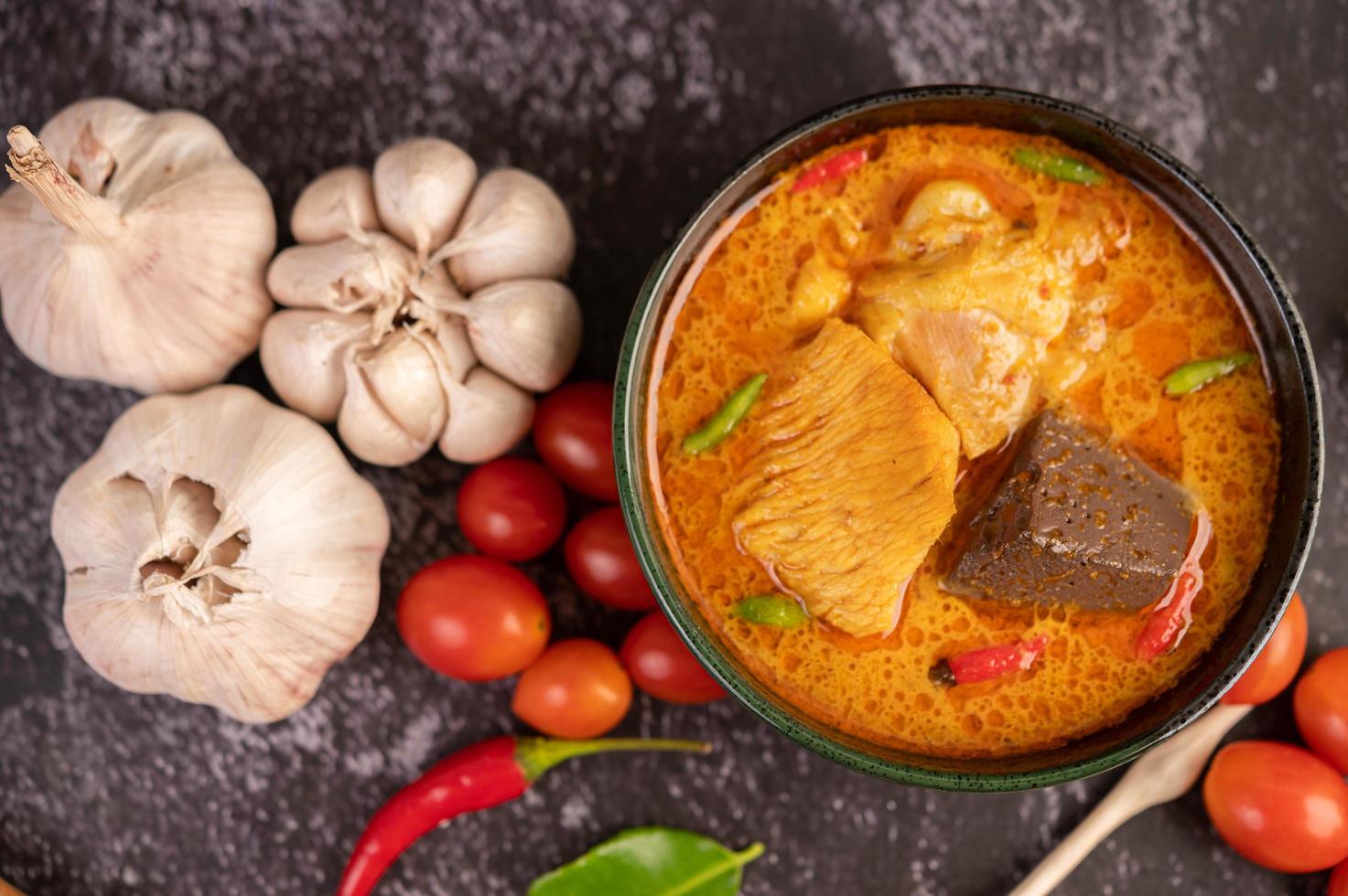 pollo al curry en una taza negra con ajo y pimientos foto