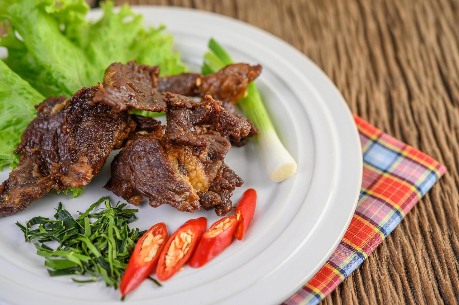 Carne de res frita comida tailandesa con cebolleta, lima, chile y ensalada foto