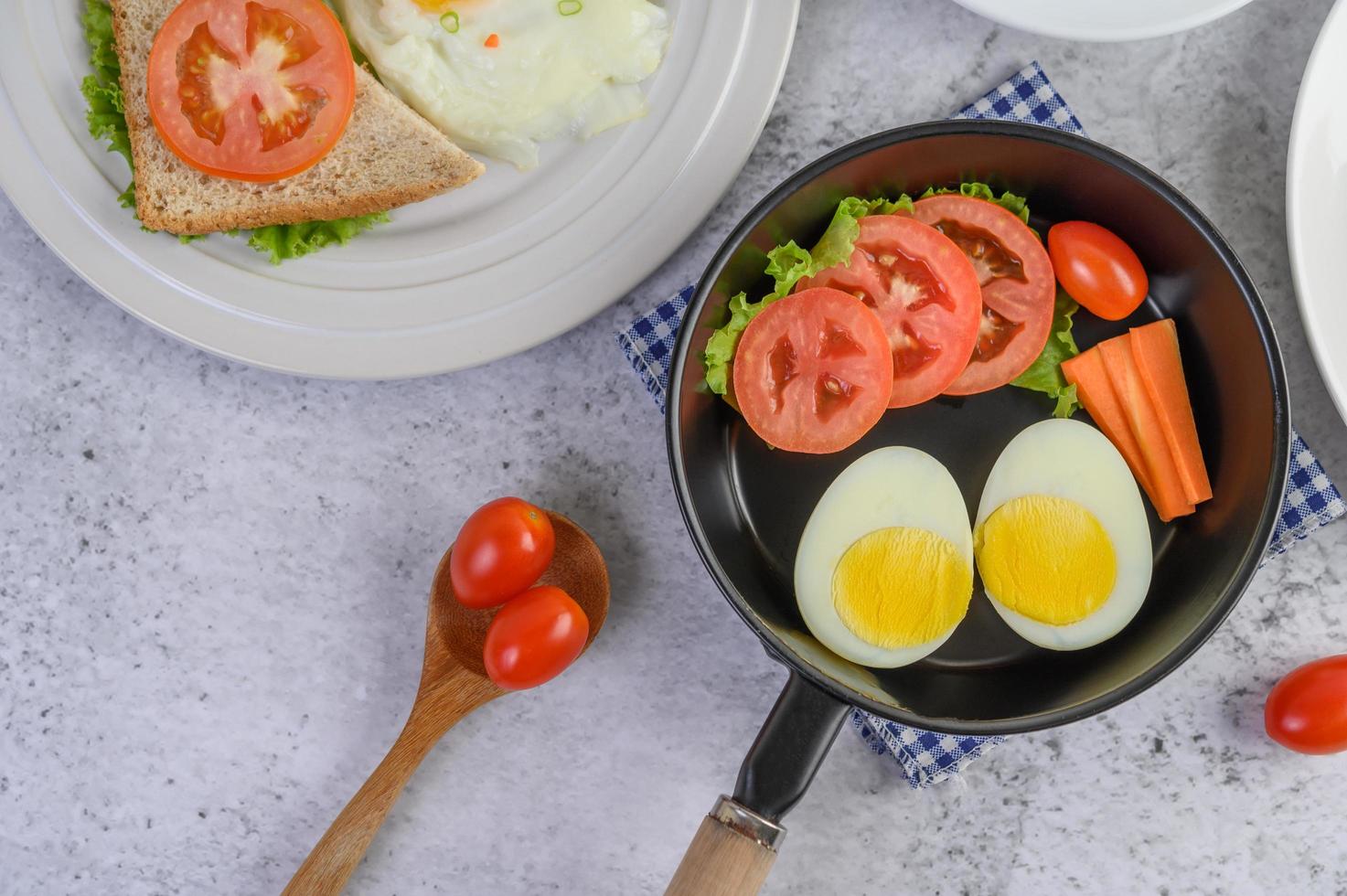 Boiled eggs, carrots, and tomatoes in a pan with tomatoes photo