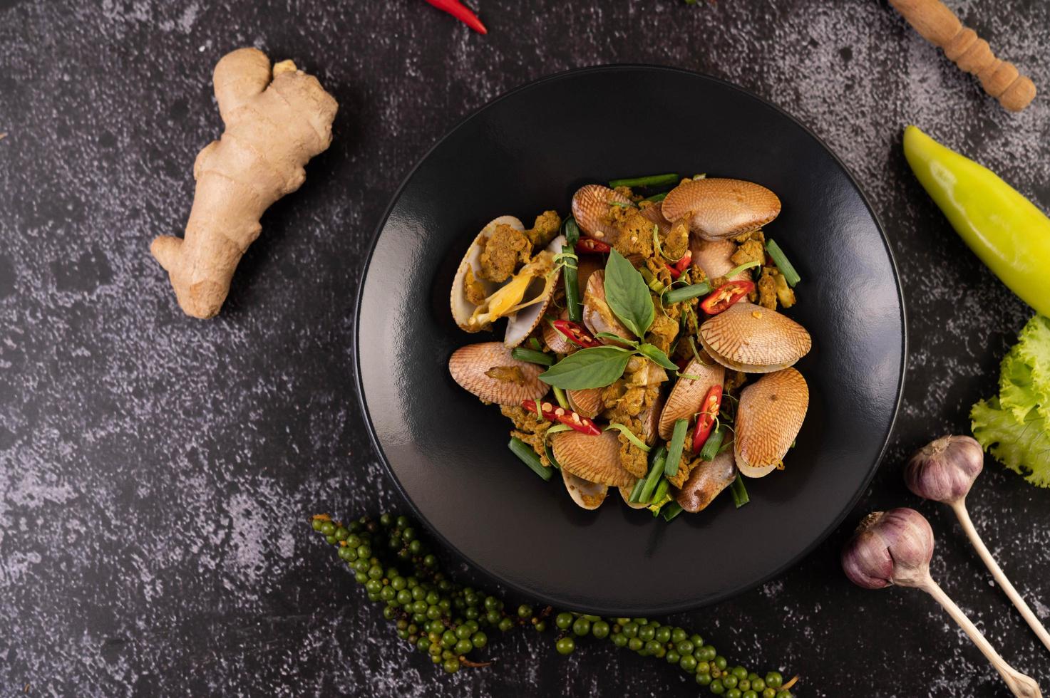 Clams fried with curry powder on a black plate photo