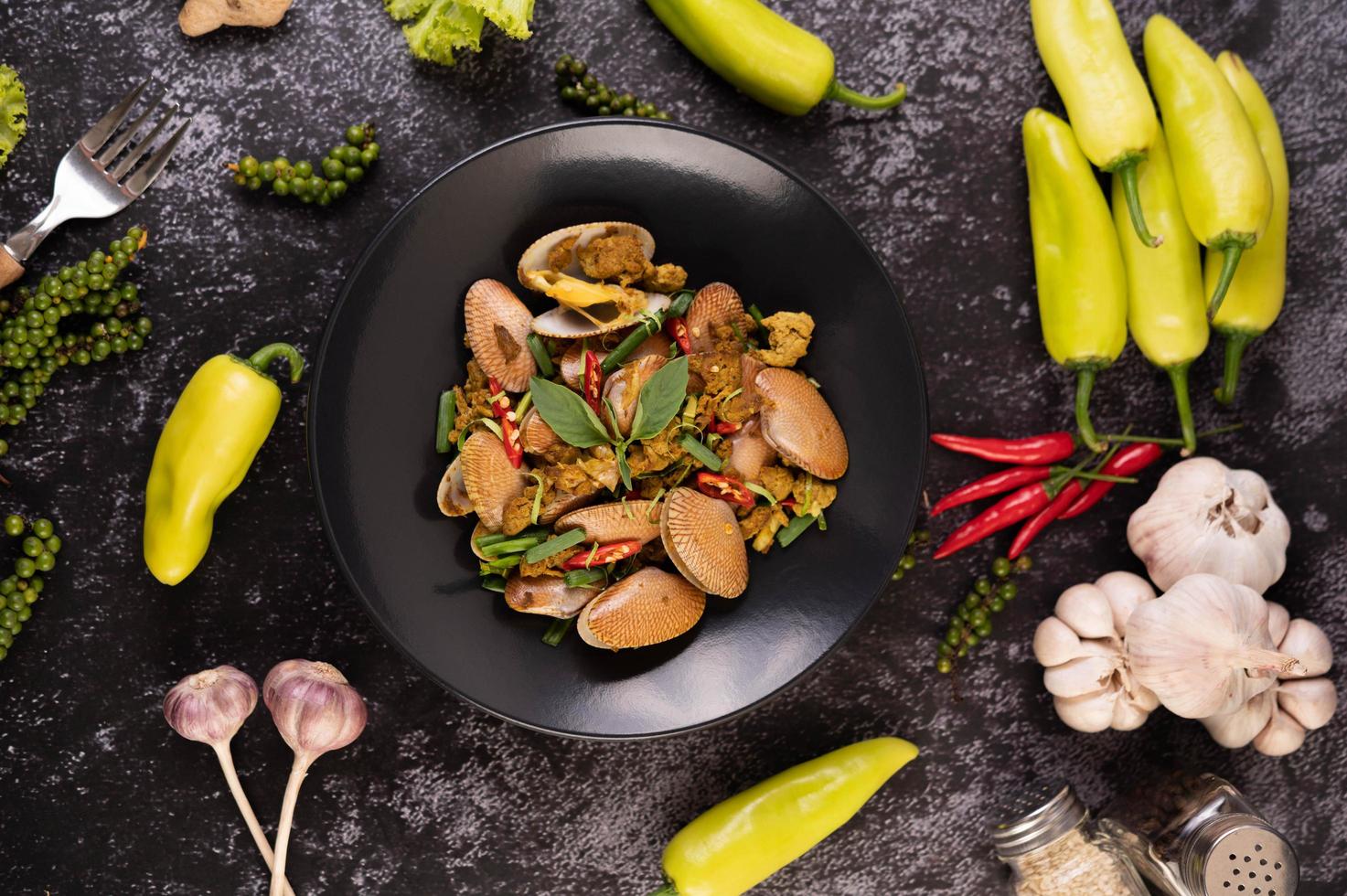 Clams fried with curry powder on a black plate photo