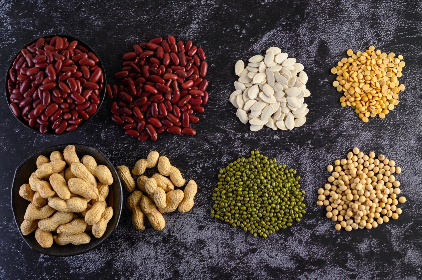 Legumes and beans assorted on a black cement surface photo