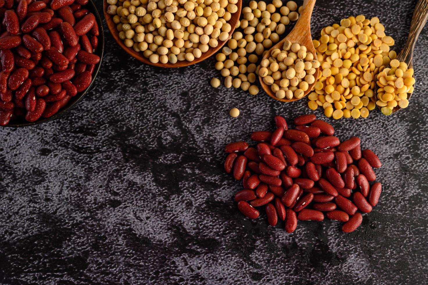 Legumes and beans assorted on a black cement surface photo