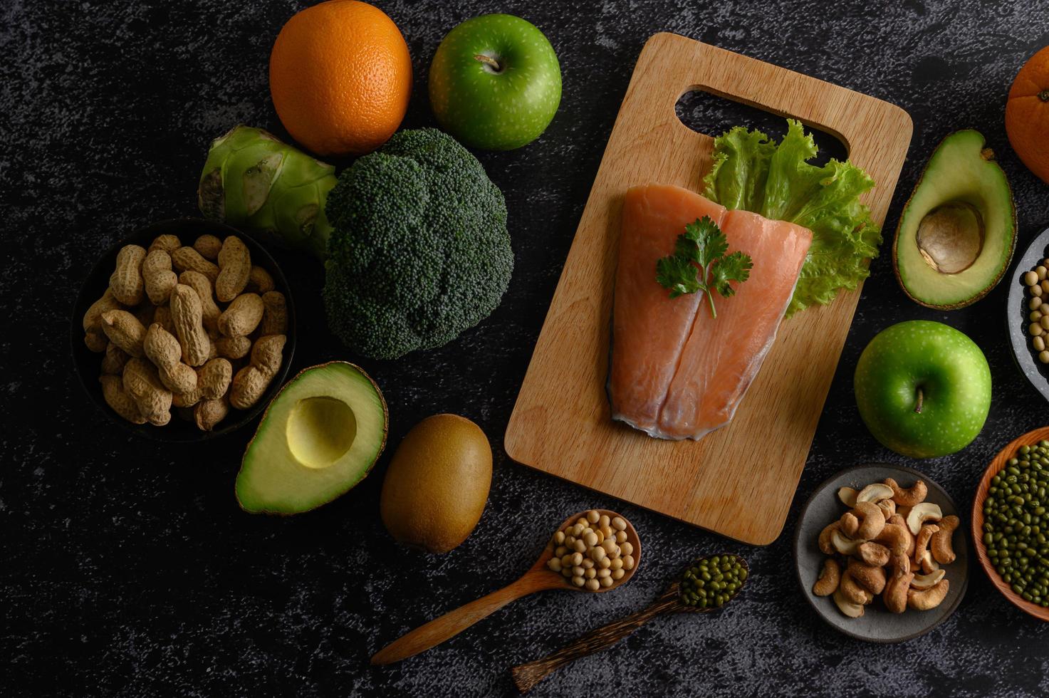 Legumbres, frutas y pescado salmón sobre una tabla de cortar de madera foto