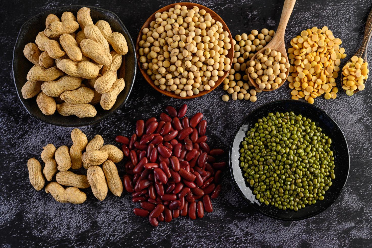 Legumes and beans assorted on a black cement surface photo