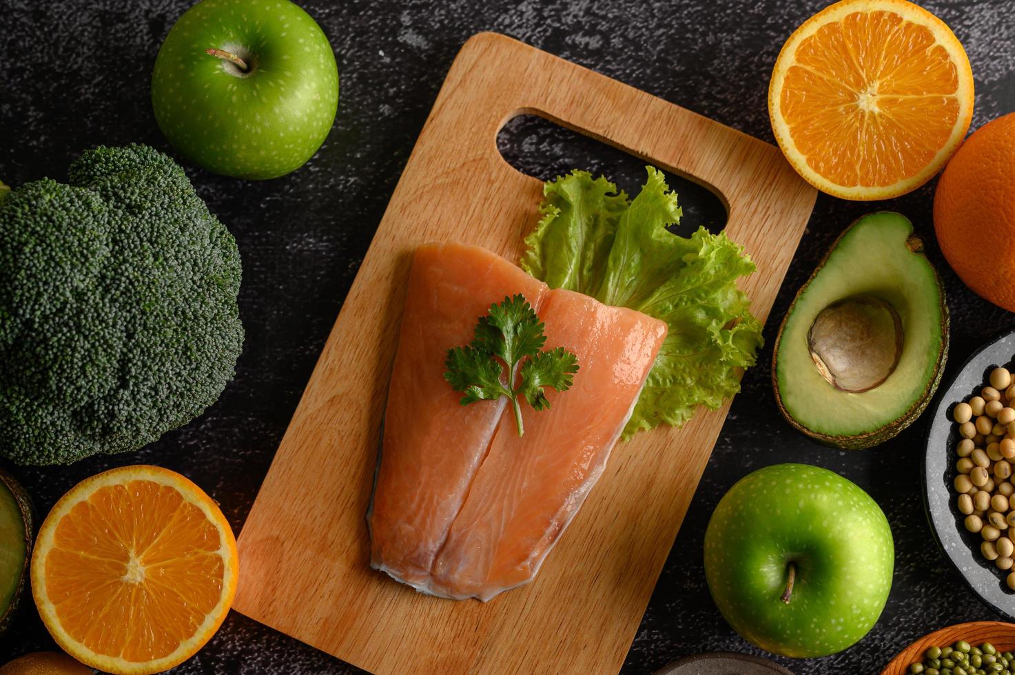 Legumes, fruit and salmon fish on a wooden chopping board photo