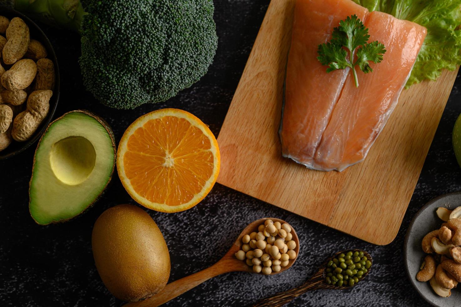 Legumbres, frutas y pescado salmón sobre una tabla de cortar de madera foto