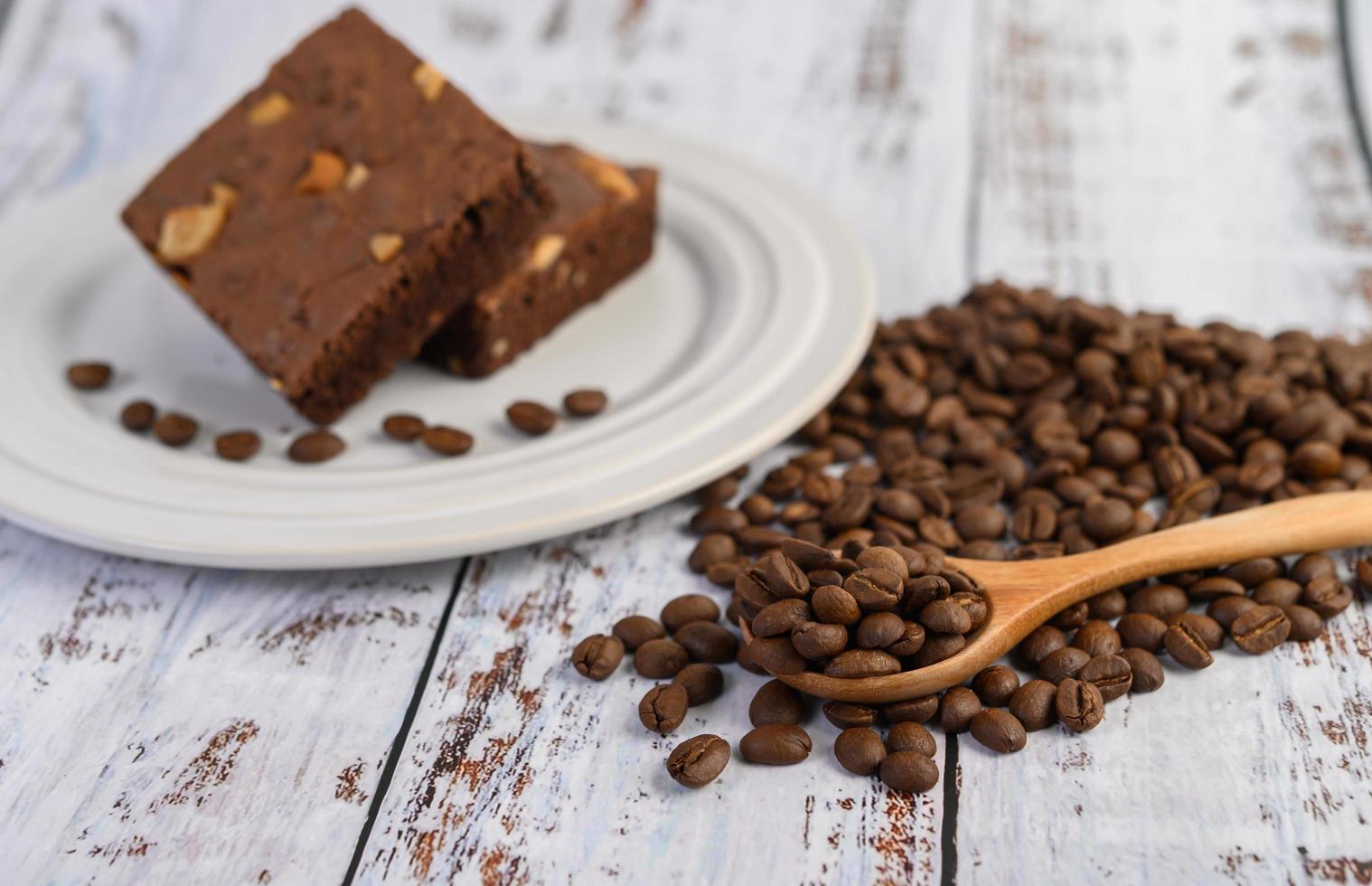 Brownies de chocolate en una placa blanca y granos de café en una cuchara de madera foto