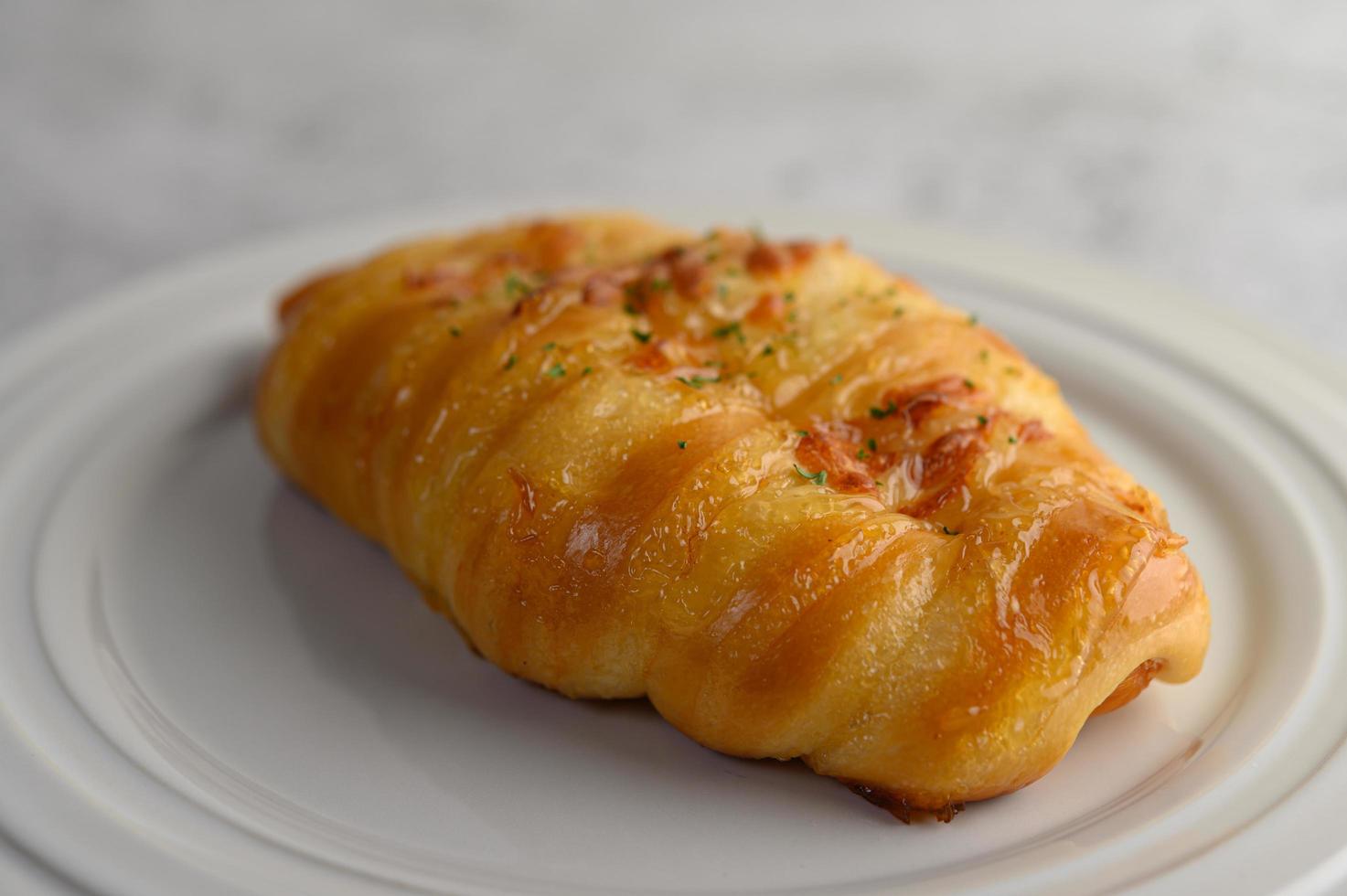 A sausage bread roll with hotdog on white plate photo