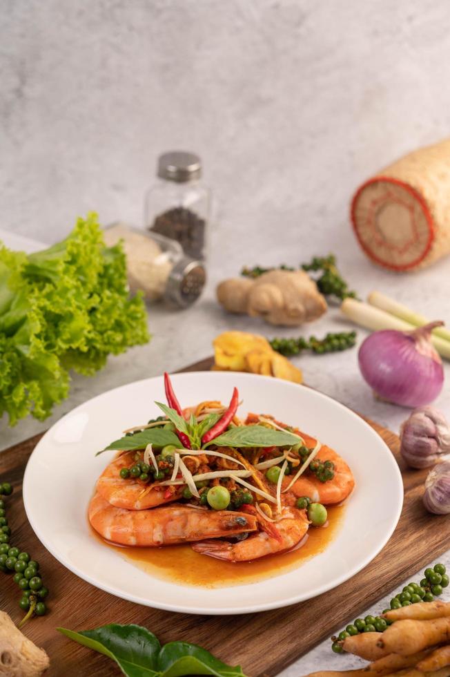 Chu-chi shrimp on a plate with fresh pepper seeds photo