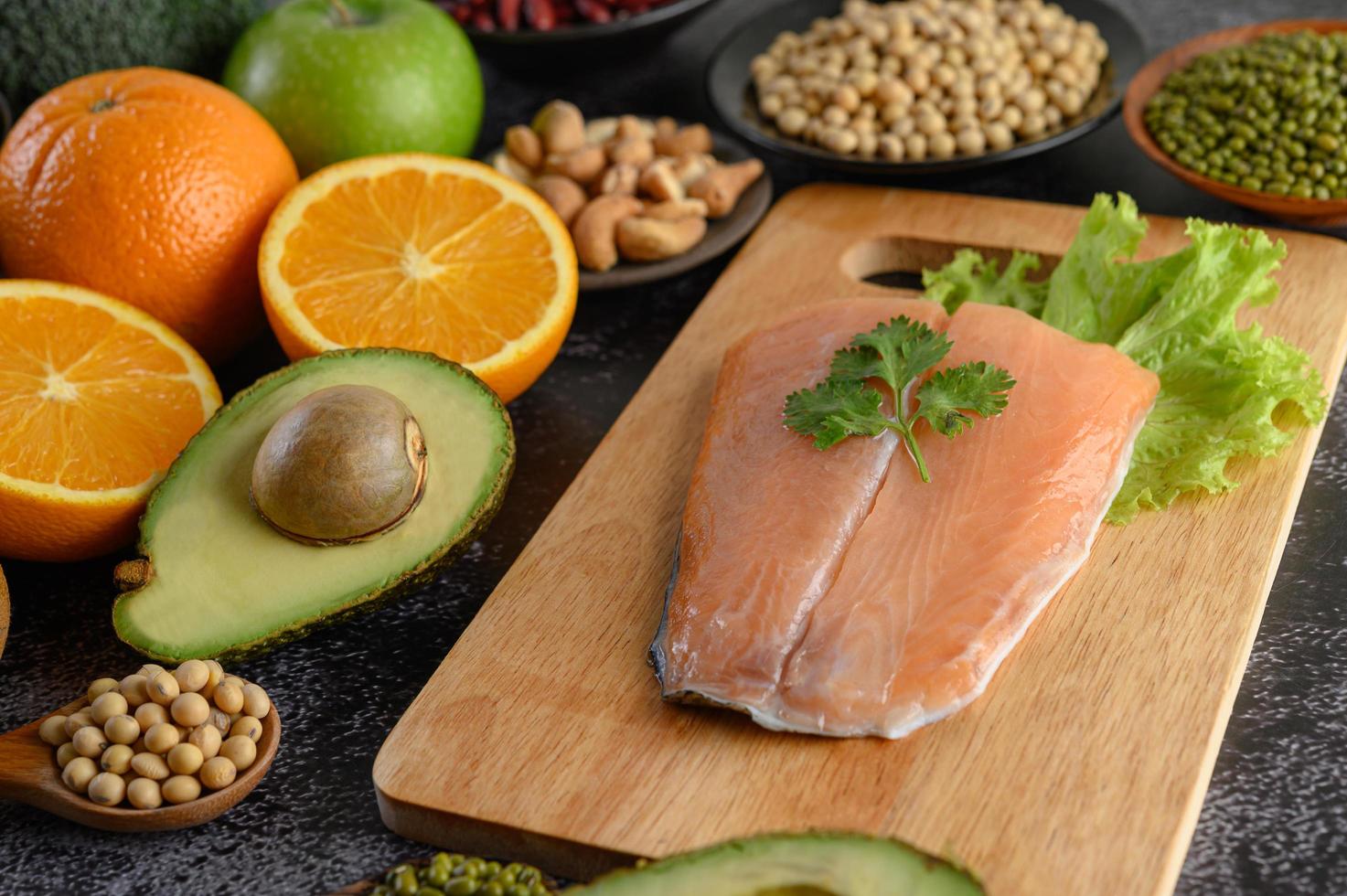 Legumes, fruit and salmon fish on a wooden chopping board photo