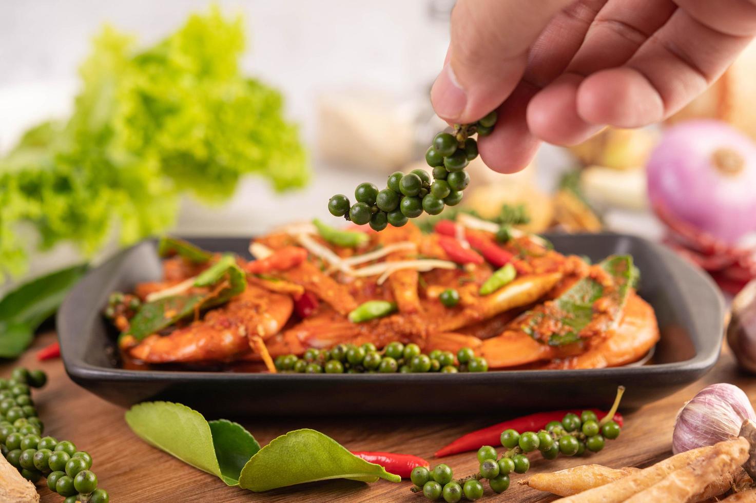 Chu-chi shrimp on a plate with fresh pepper seeds photo