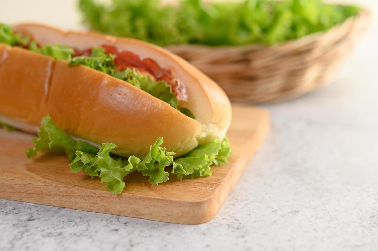 Hotdog with lettuce on wood cutting board photo