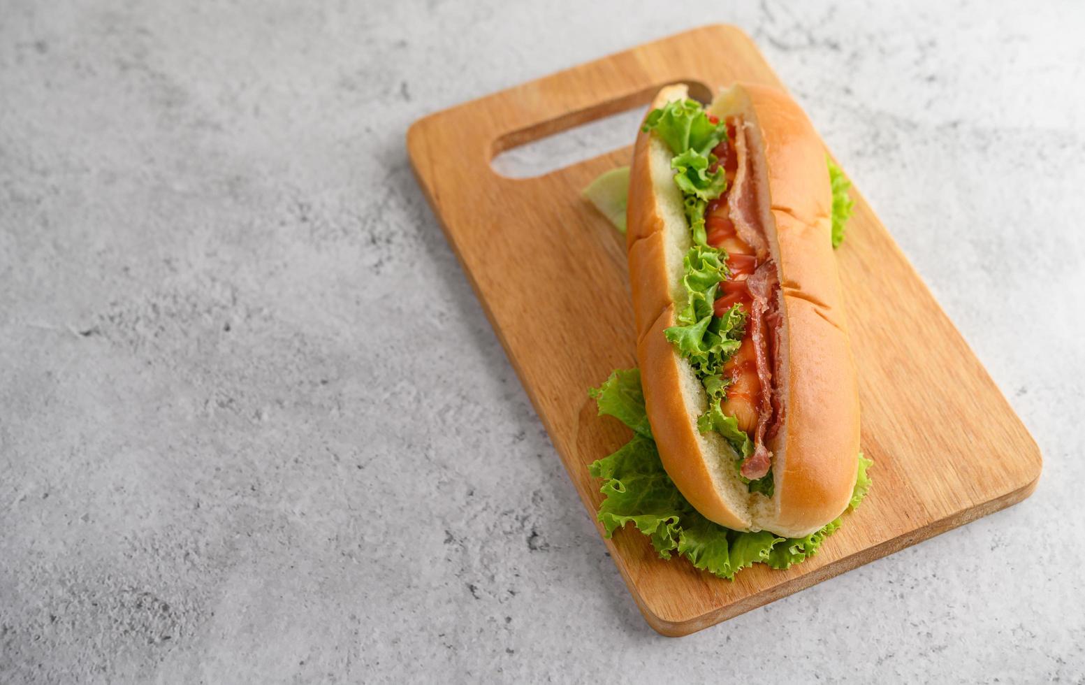 Large hotdog with lettuce on wood cutting board photo