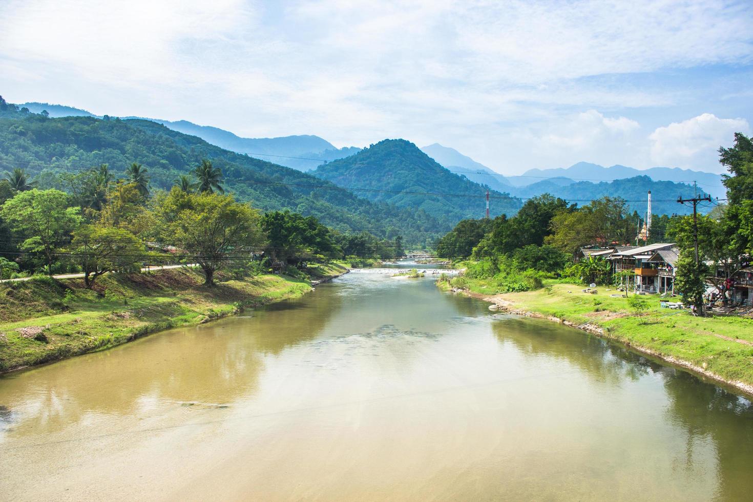 River, forest, and mountains with cloudy blue sky photo